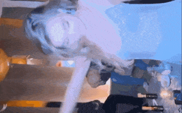 a woman in a blue dress is laying on her back in front of a table with wine bottles .