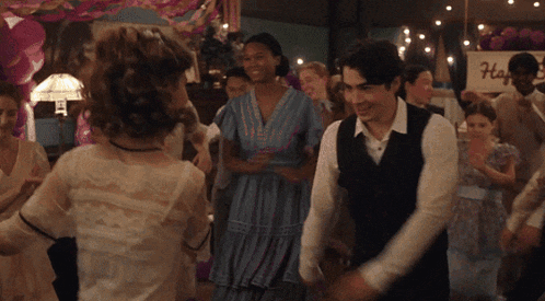 a group of people are dancing in a room with a sign that says h.