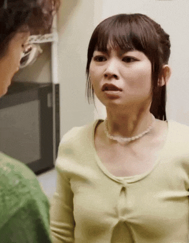 a woman wearing a green shirt and a pearl necklace