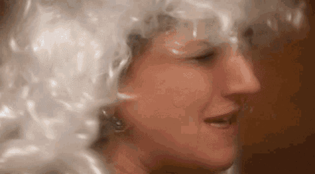 a close up of a woman 's face with a white wig on