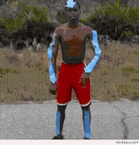 a shirtless man wearing red shorts and blue gloves