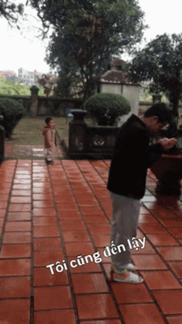 a man standing on a brick walkway with the words toi cùng den lay written on the bottom