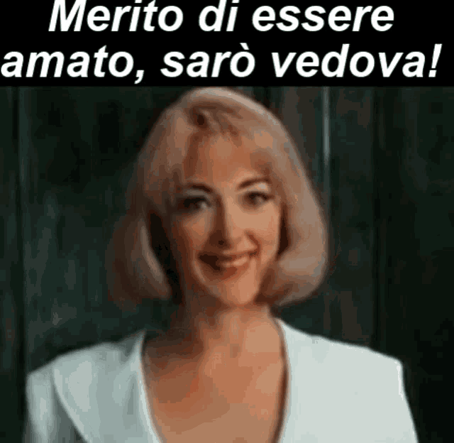 a woman in a white suit is smiling in front of a blackboard and the words merito di essere amato saro vedova .