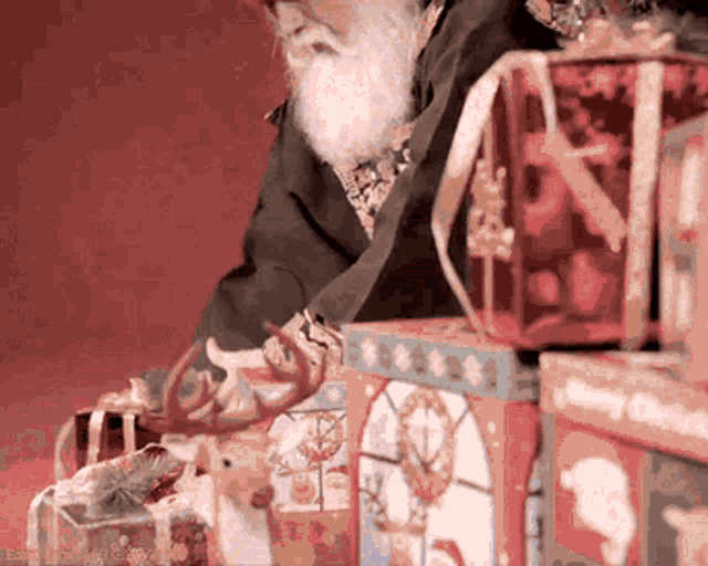 a man with a beard is standing in front of a stack of christmas presents