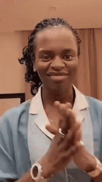 a woman in a blue shirt is clapping her hands .