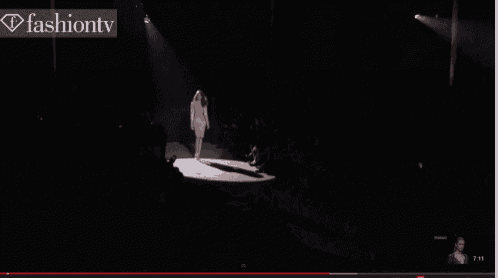 a woman is walking down a runway in front of a fashion tv banner