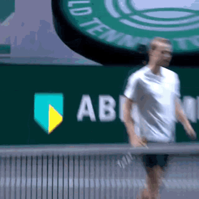 a man is playing tennis in front of a sign that says ' ab ' on it