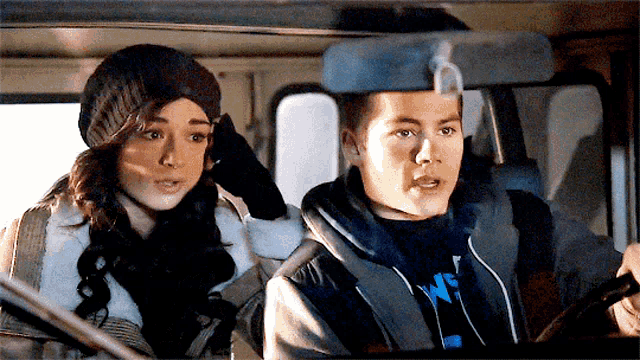 a man and a woman are sitting in a car and the man is wearing a sweatshirt that says ' ws '
