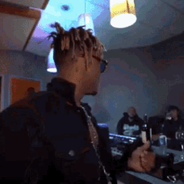 a man wearing sunglasses and dreadlocks is standing in a dark room
