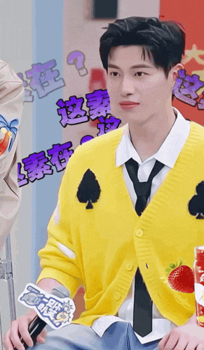 a young man wearing a yellow sweater and tie is holding a microphone
