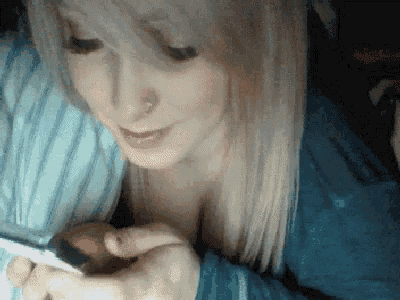 a woman in a blue shirt is looking at a cell phone .