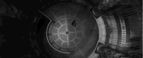a black and white photo of a circular building with a clock on it .