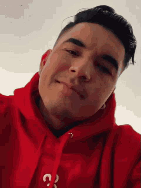 a man wearing a red hoodie has a question mark on the front