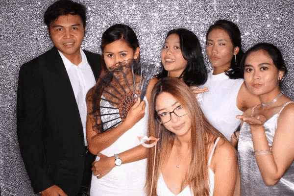 a group of people are posing for a picture with one woman holding a fan