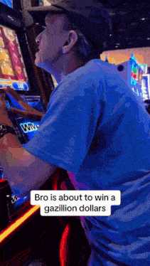a man in a blue shirt is playing a slot machine in an amusement park .