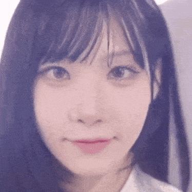 a close up of a young woman 's face with a purple haircut and bangs .