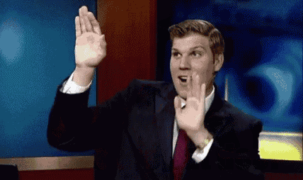 a man in a suit and tie is making a funny face while waving his hand in the air .