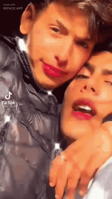 a couple of young men are standing next to each other and one of them is wearing lipstick .