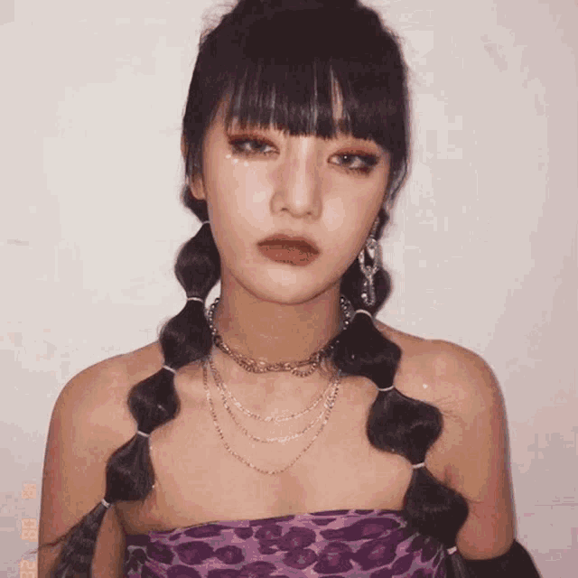 a woman wearing a purple top with a leopard print and a necklace