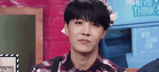 a young man wearing a flower crown is making a funny face .