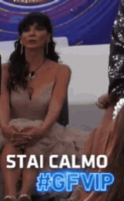 a woman in a dress is sitting on a couch with the words stai calmo #gfvip on the bottom .