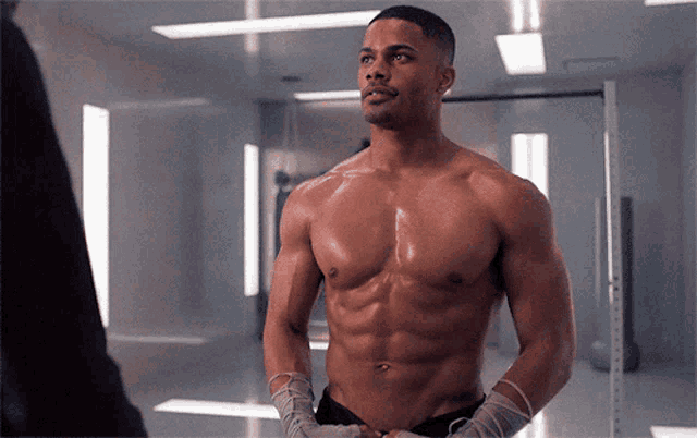 a shirtless man with boxing wraps around his arms stands in front of a mirror