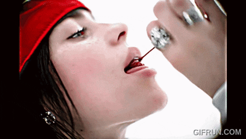 a close up of a woman eating a cherry with a gifrun.com watermark