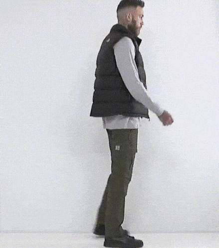 a man with a beard is wearing a black north face vest