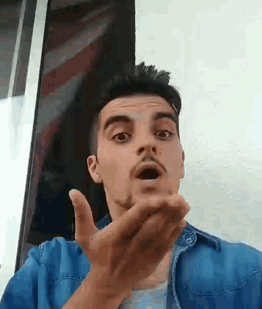 the man is wearing a blue shirt and making a funny face .