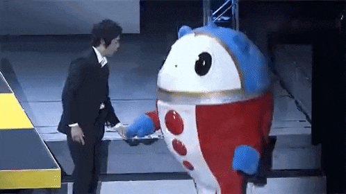 a man in a suit is standing next to a mascot in a red , white and blue costume .