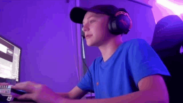 a young boy wearing headphones and a hat is playing a video game on a computer .