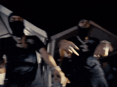 a man wearing a black mask is dancing in front of a crowd of people .