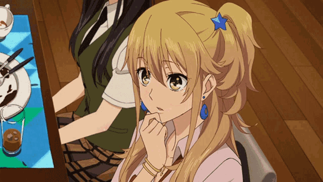 a blonde anime girl with a blue star in her hair is sitting at a table