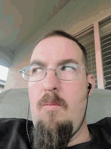 a man with glasses and a beard looks down