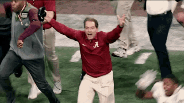 a man in a red shirt with the letter a on it is running on a field