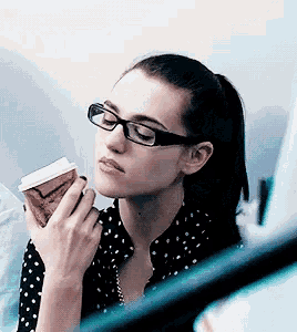 a woman with glasses is holding a cup of coffee