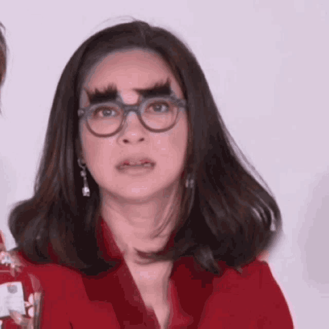 a woman wearing glasses and fake eyebrows is making a face .