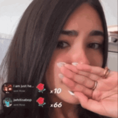 a woman is covering her mouth with her hand and a few roses are visible in the background