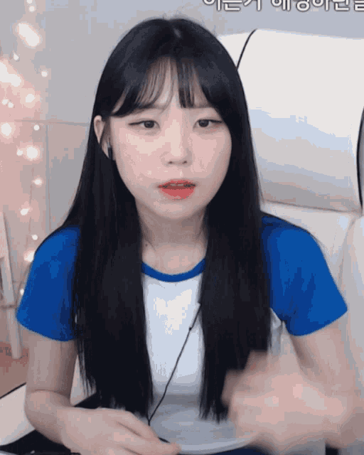 a girl in a blue shirt is sitting in front of a white chair