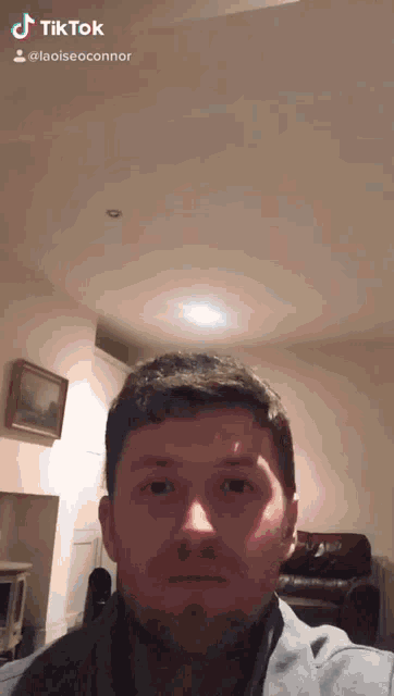 a man is taking a selfie in a living room with a tiktok watermark