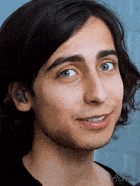 a close up of a young man 's face with long hair and blue eyes .