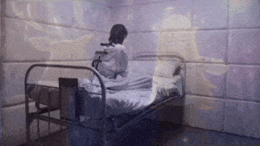 a woman in a straight jacket sits in a bed