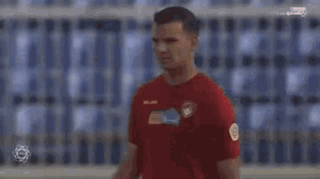 a man wearing a red soccer jersey is standing on a field .