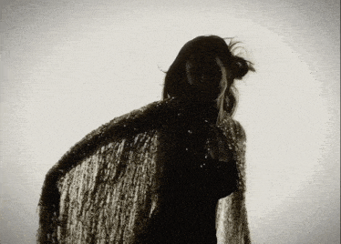a silhouette of a woman with a cape on