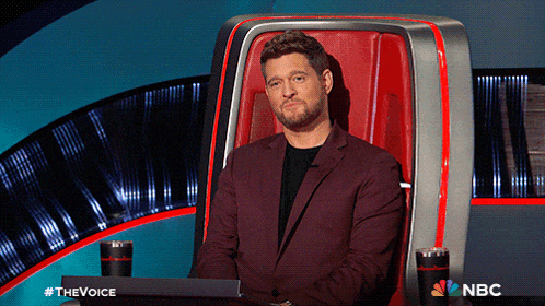 a man in a suit sits in a chair with a nbc logo on the bottom