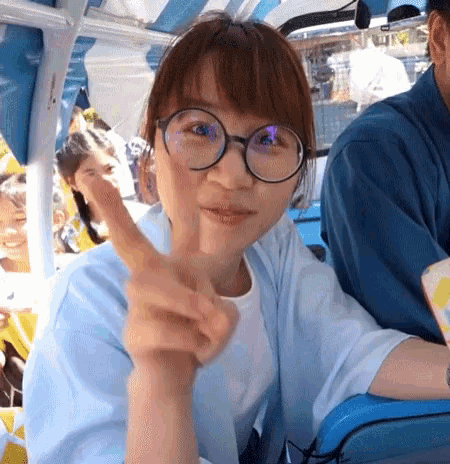 a woman wearing glasses and a white shirt is giving a peace sign