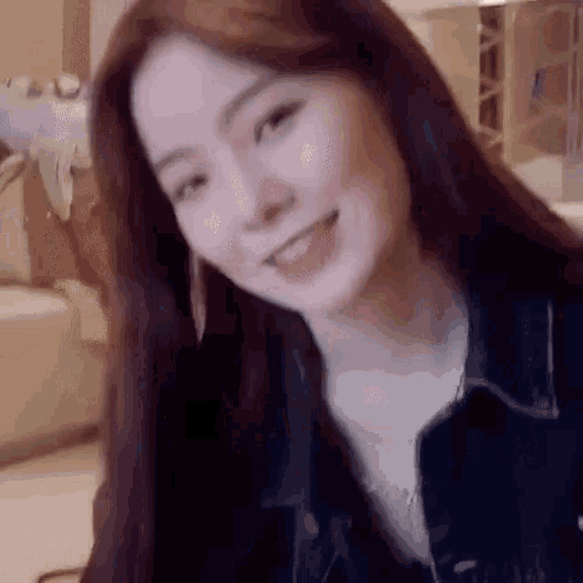 a woman with long hair is smiling and looking at the camera while wearing a denim jacket .