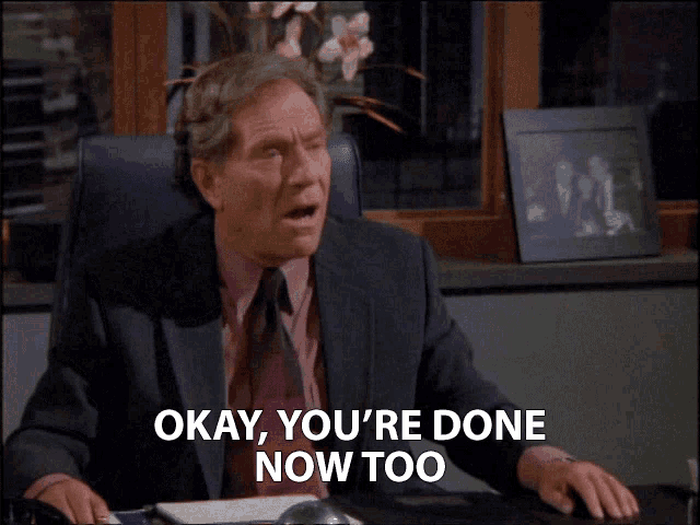 a man in a suit and tie is sitting at a desk with his mouth open and says okay you 're done now too