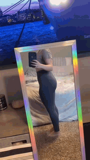 a woman is taking a selfie in front of a mirror while wearing leggings .