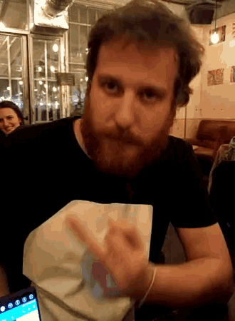 a man with a beard is sitting at a table holding a napkin